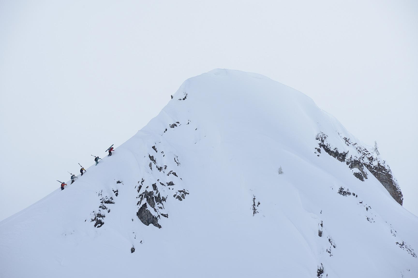 A line of skiers dwarfed by a snowy alpine ridge at Island Lake