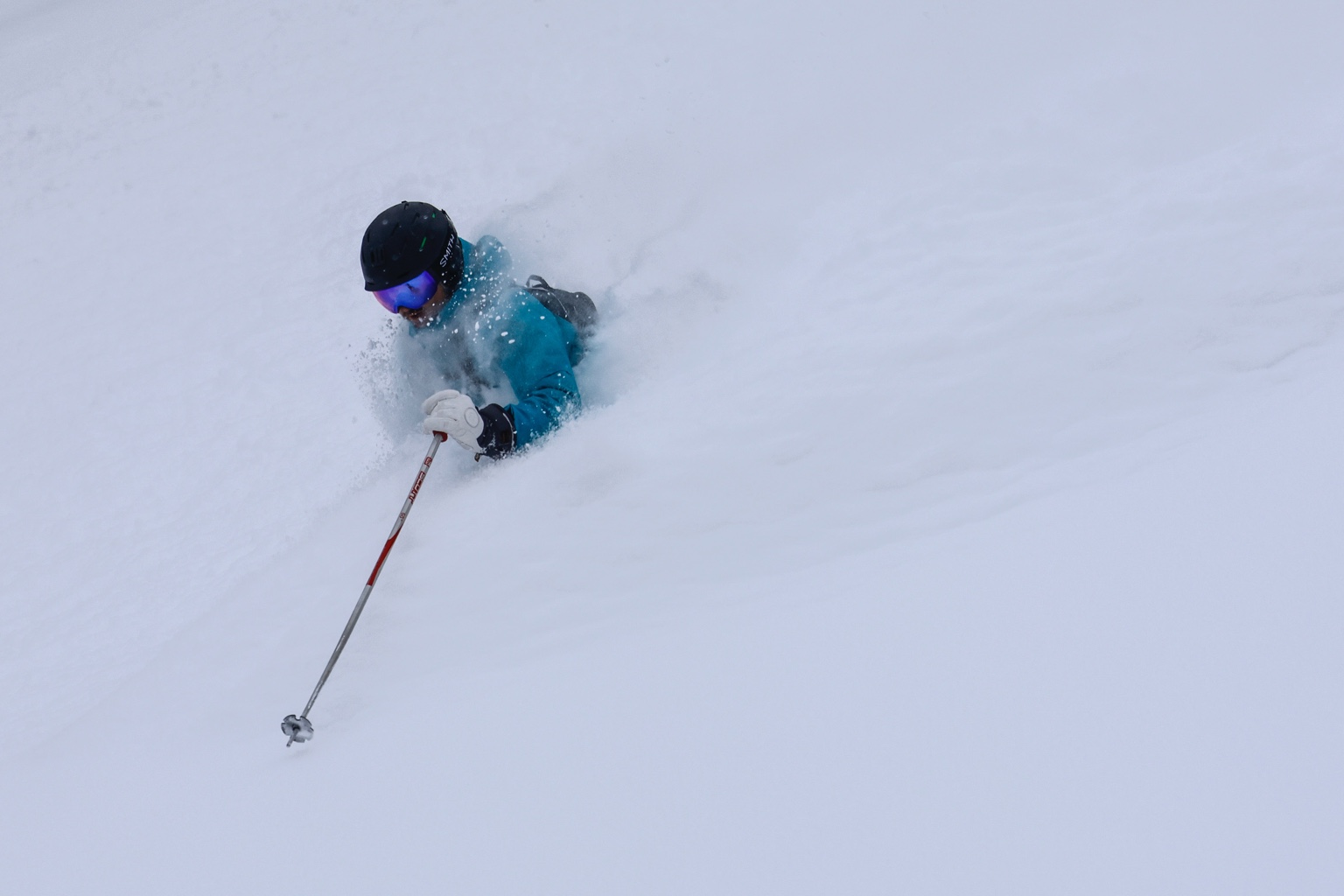Chad Byers skiing through deep powder in a turquoise jacket