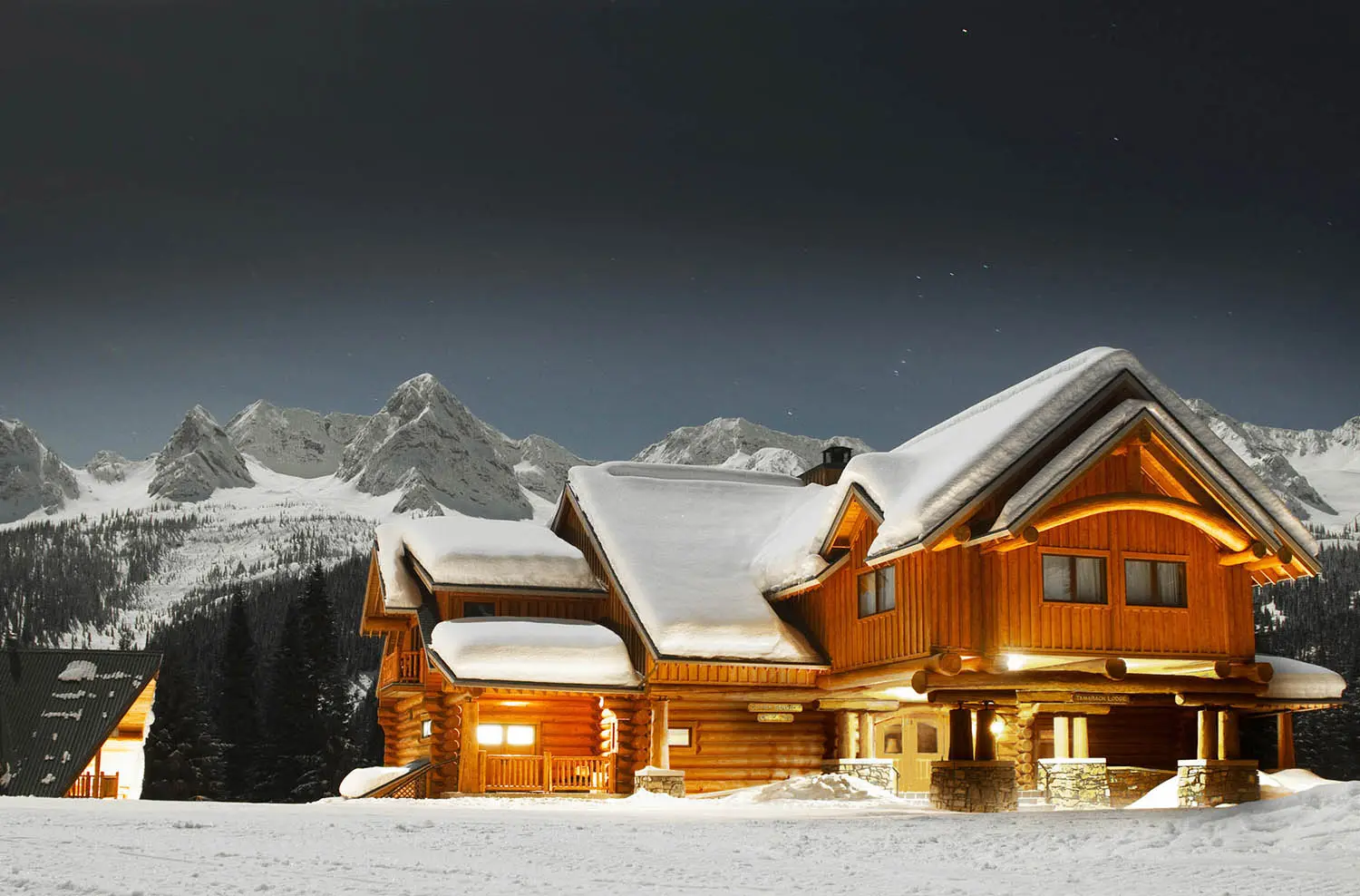 Tamarack Lodge glowing at night beneath the Three Bears peaks