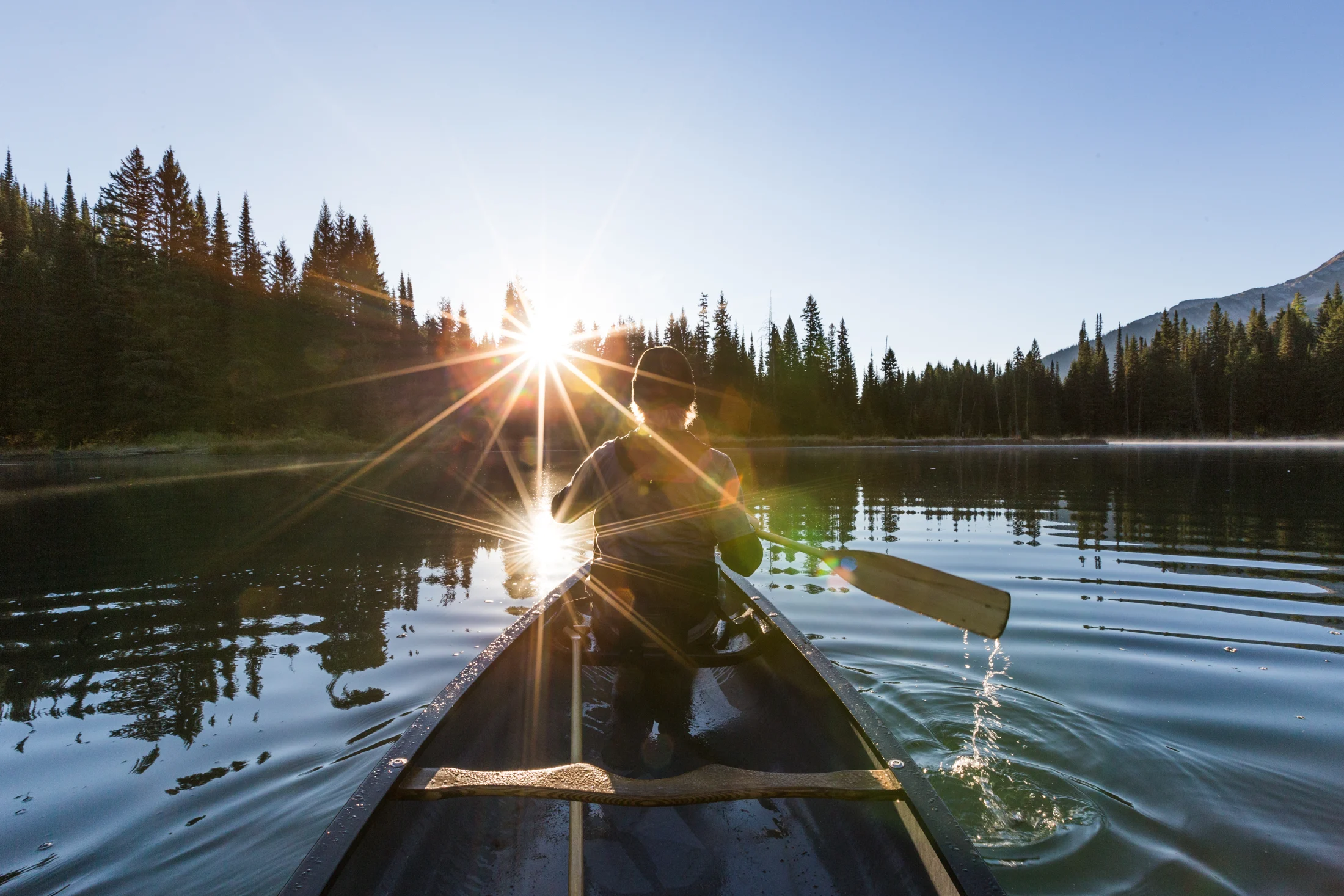 Sunlight across Island Lake seen from a canoe on the calm water