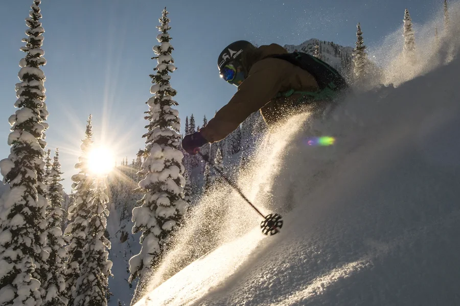 A skier turning through sunlit powder at Island Lake