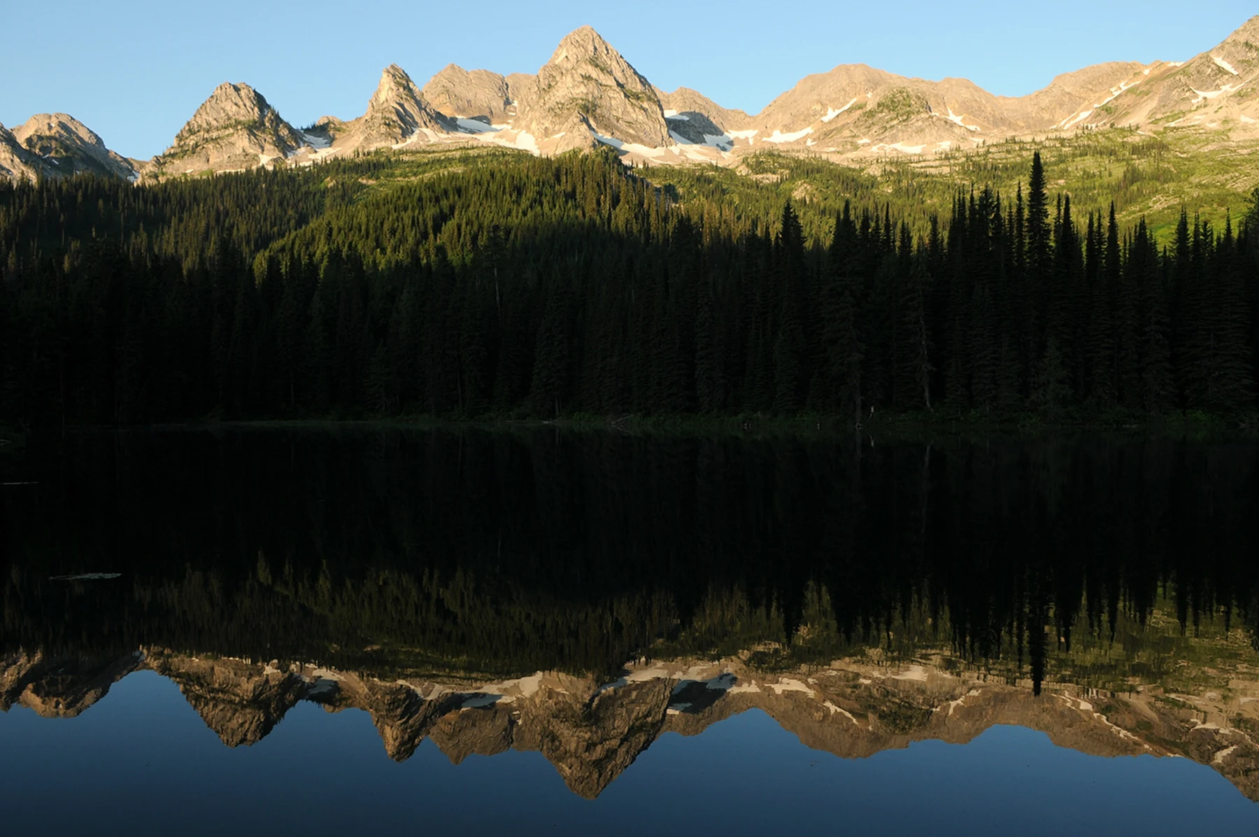 The Three Bears peaks and forest reflected in Island Lake from the boat launch.