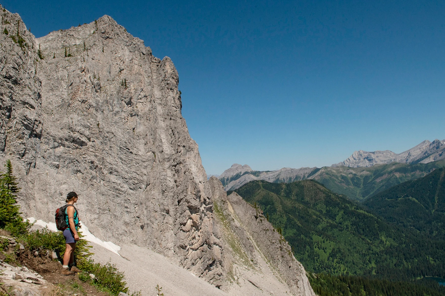 A hiker beside the sheer rock face on the east side of Baby Bear peak along Goldilocks Trail.