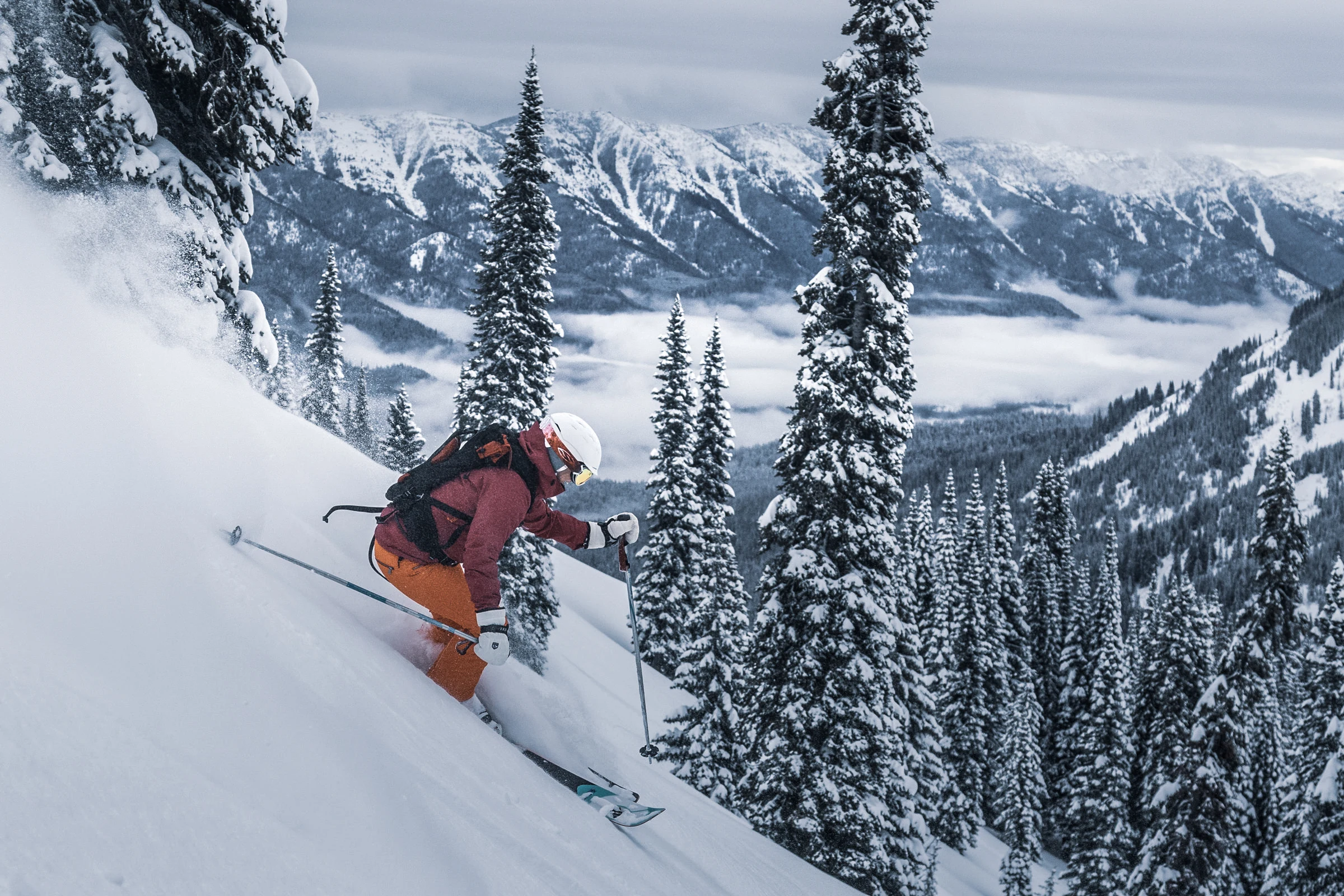 A skier carving through deep powder above the Lizard Range at Island Lake
