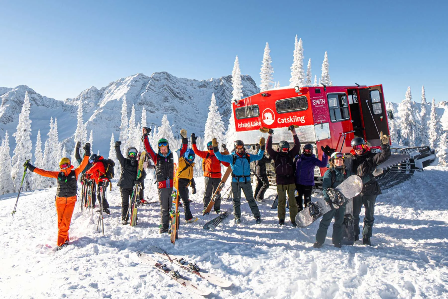 A group of Island Lake guests celebrating beside a red snowcat in the high alpine